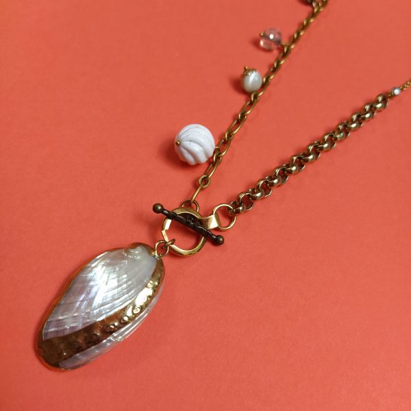 Collier en laiton bronze composé de différentes chaînes  de perles blanches et nacrées aux formes diverses dont le pendentif est un coquillage émaillé.