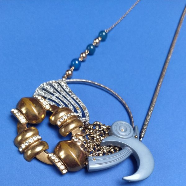 Sautoir composé d'une chaîne de collier  d'un bracelet argenté sur lequel sont fixés une broche Art Deco strassée  un clip de foulard Art Deco  un pendentif filigrané plus récent et une broche plastique des années 1980.