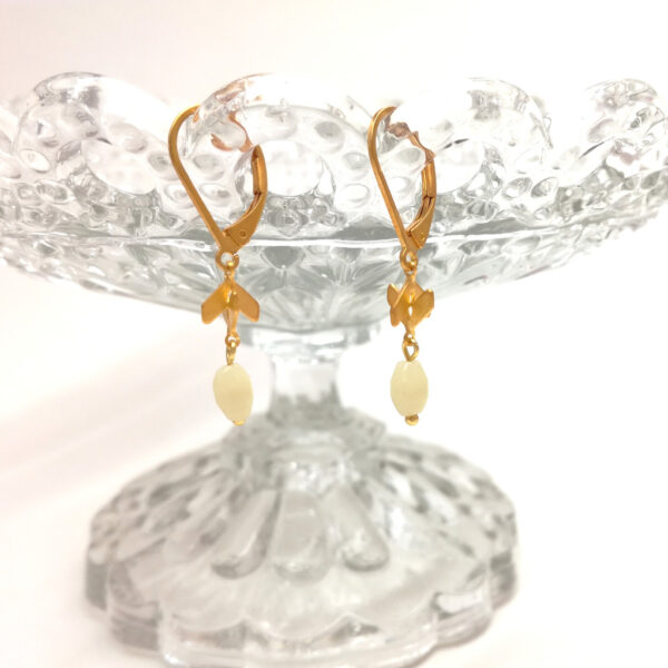 D’anciennes perles de chapelet blanc crème montées sur des petites flèches entremêlées et des dormeuses dorées à l’or fin.
