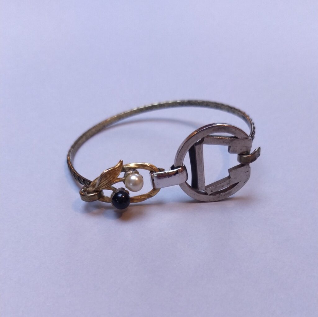 Jonc en métal bronze réalisé à partir d'un ancien bracelet composé d'un élément de boucle de ceinture et d'une ancienne boucle d'oreille surmontée de perles de verre noire et nacrée.