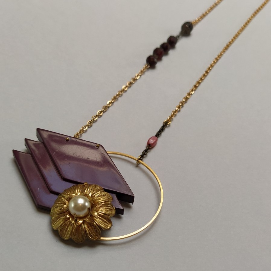 Collier composé d'un élément de boucle de ceinture des années 1980 et d'un clip d'oreille orphelin  le tout monté sur un cercle de laiton doré à l'or fin. La chaîne dorée est composée d'éléments de chapelet rubis et rose.